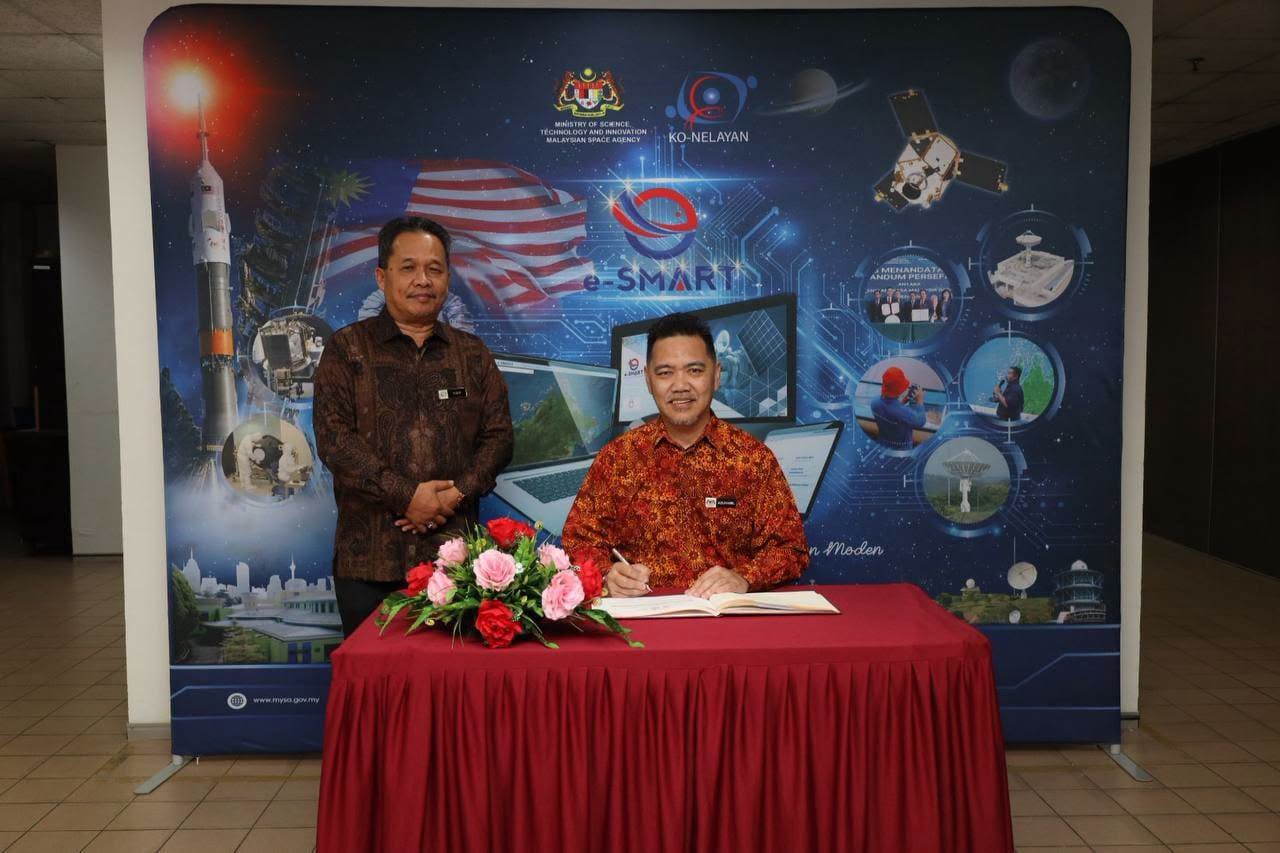 Pengurus Besar Ko-Nelayan menandatangani buku pelawat di hadapan latar e-SMART MYSA dan Ko-Nelayan